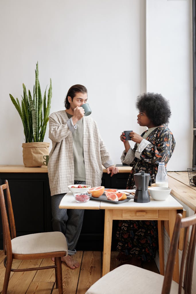 A couple enjoys coffee and breakfast together in their cozy, sunlit home.