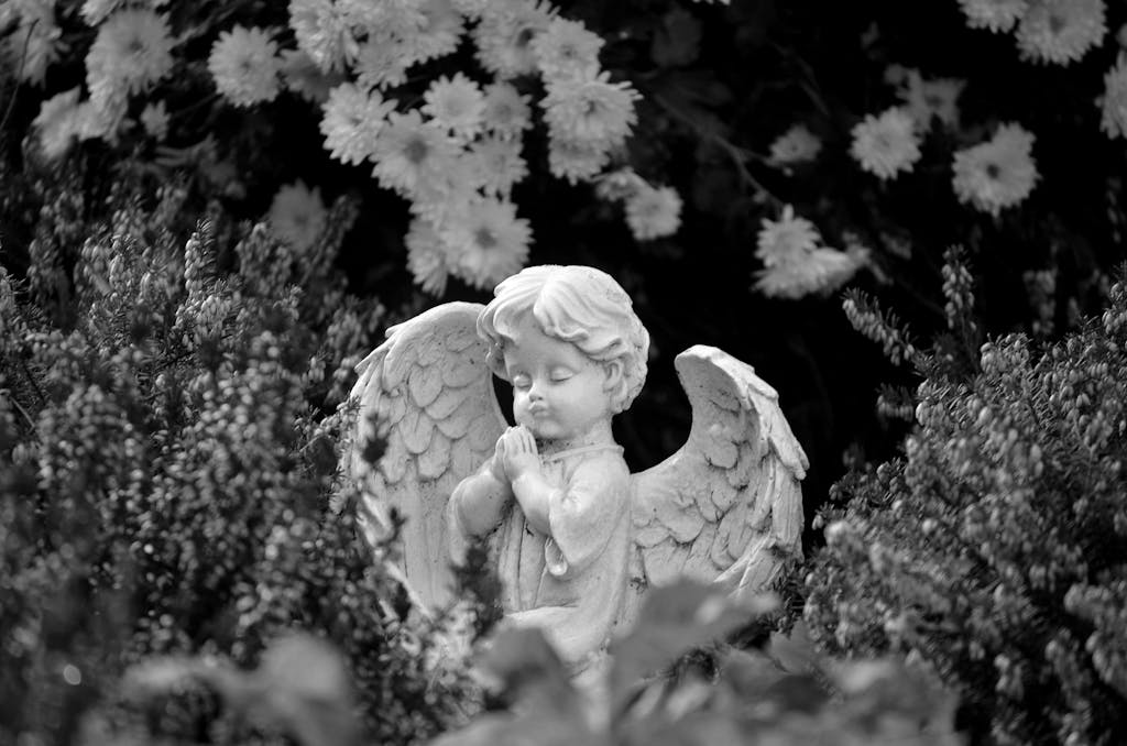 A peaceful stone angel statue surrounded by blooming flowers, symbolizing tranquility and faith.