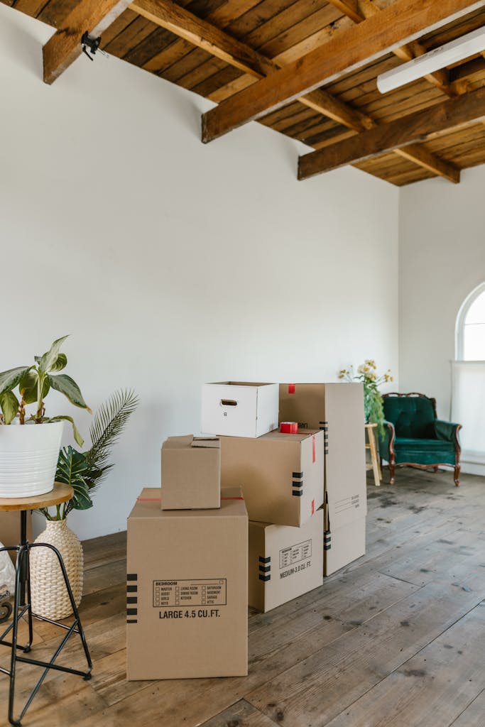 A spacious room with wooden floors and stacked cardboard boxes, ideal for moving concepts.