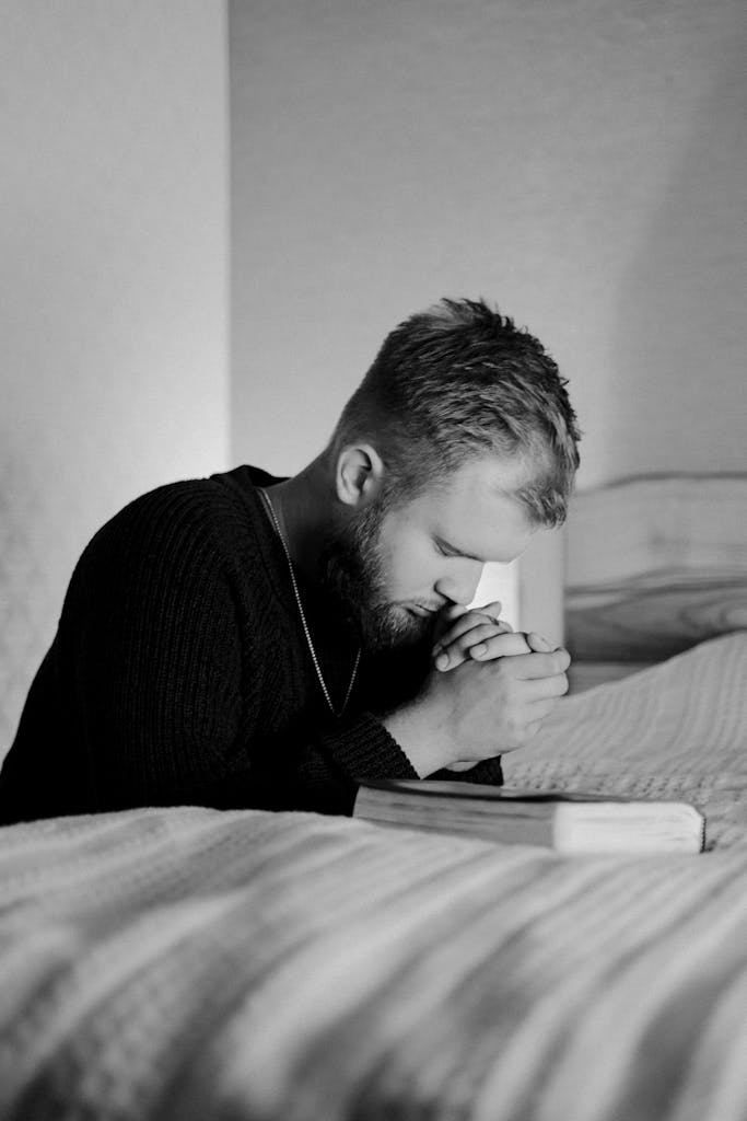 A thoughtful man in prayer at home captured in a monochrome portrait.