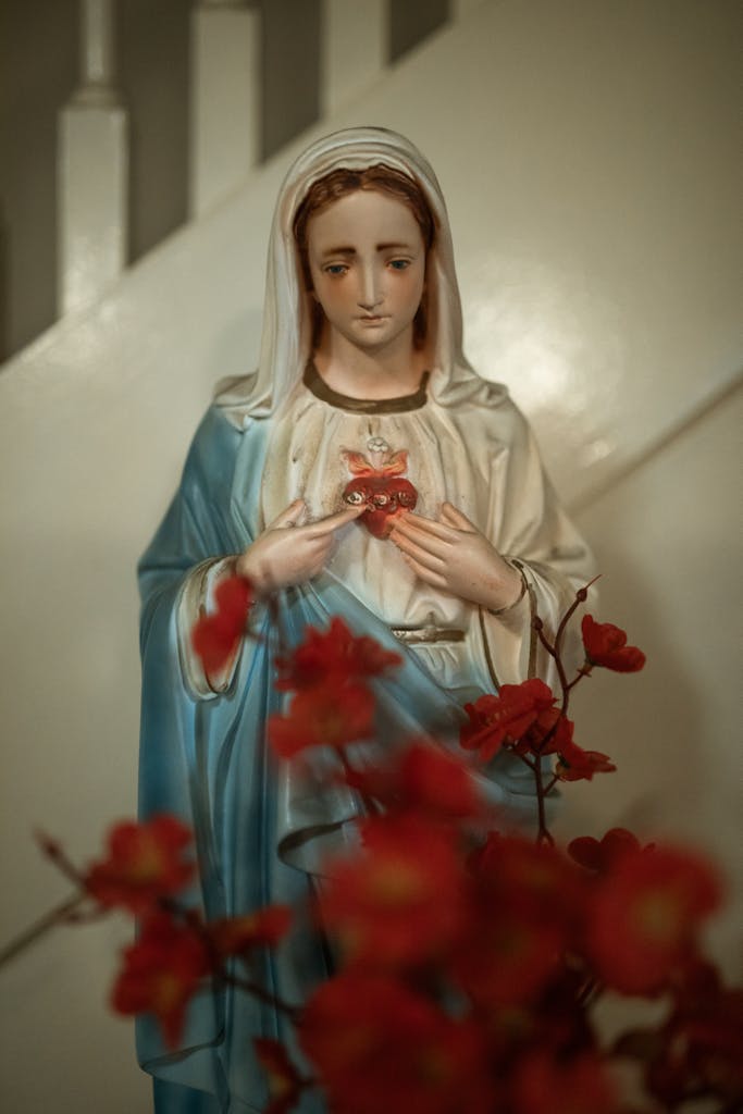 Close-up of a religious Virgin Mary statue with flowers symbolizing peace and devotion.