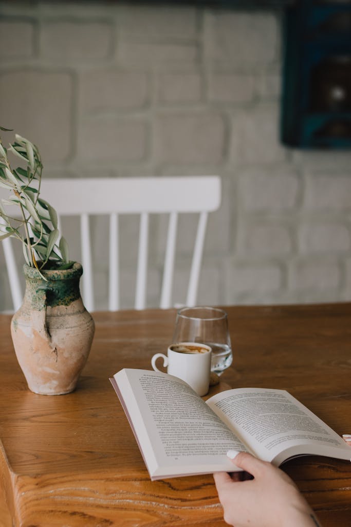 Hands reading a book with coffee in a stylish, minimalist setting. Perfect for relaxation concepts.