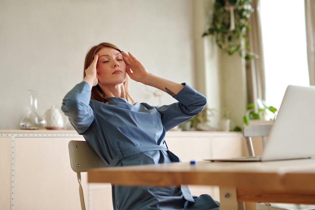 Woman experiencing stress at work, sitting at desk with a laptop, indoors.